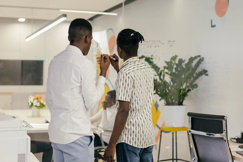 Osoba píšící strategický plán na skleněnou tabuli.